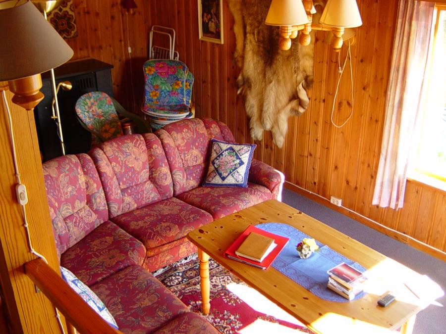 Rustikaler Wohnraum in einem norwegischen Ferienhaus mit Holzvertäfelung, Sofa und Ofen