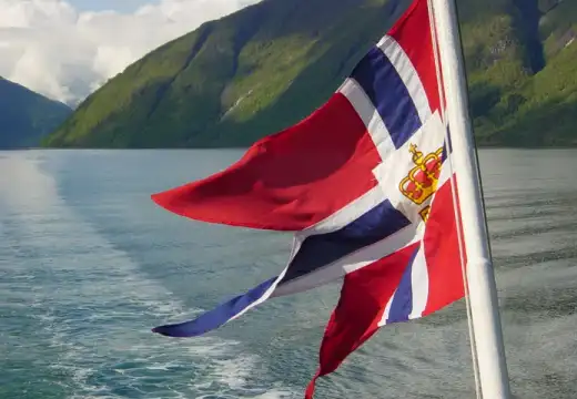 Norwegische Flagge vor einer Fjordlandschaft