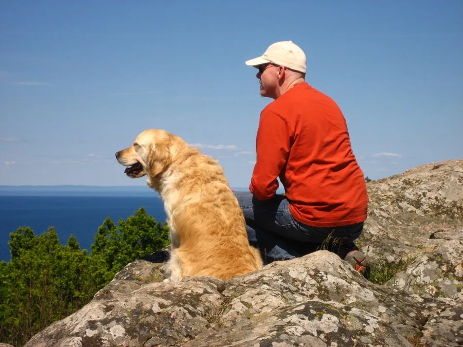 Jürgen und sein Golden Retriever blicken von einem Felsen über das Meer